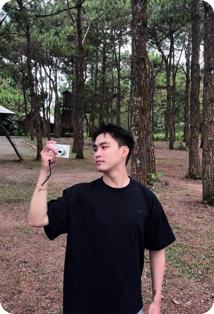Minh Duc holding a camera outdoors